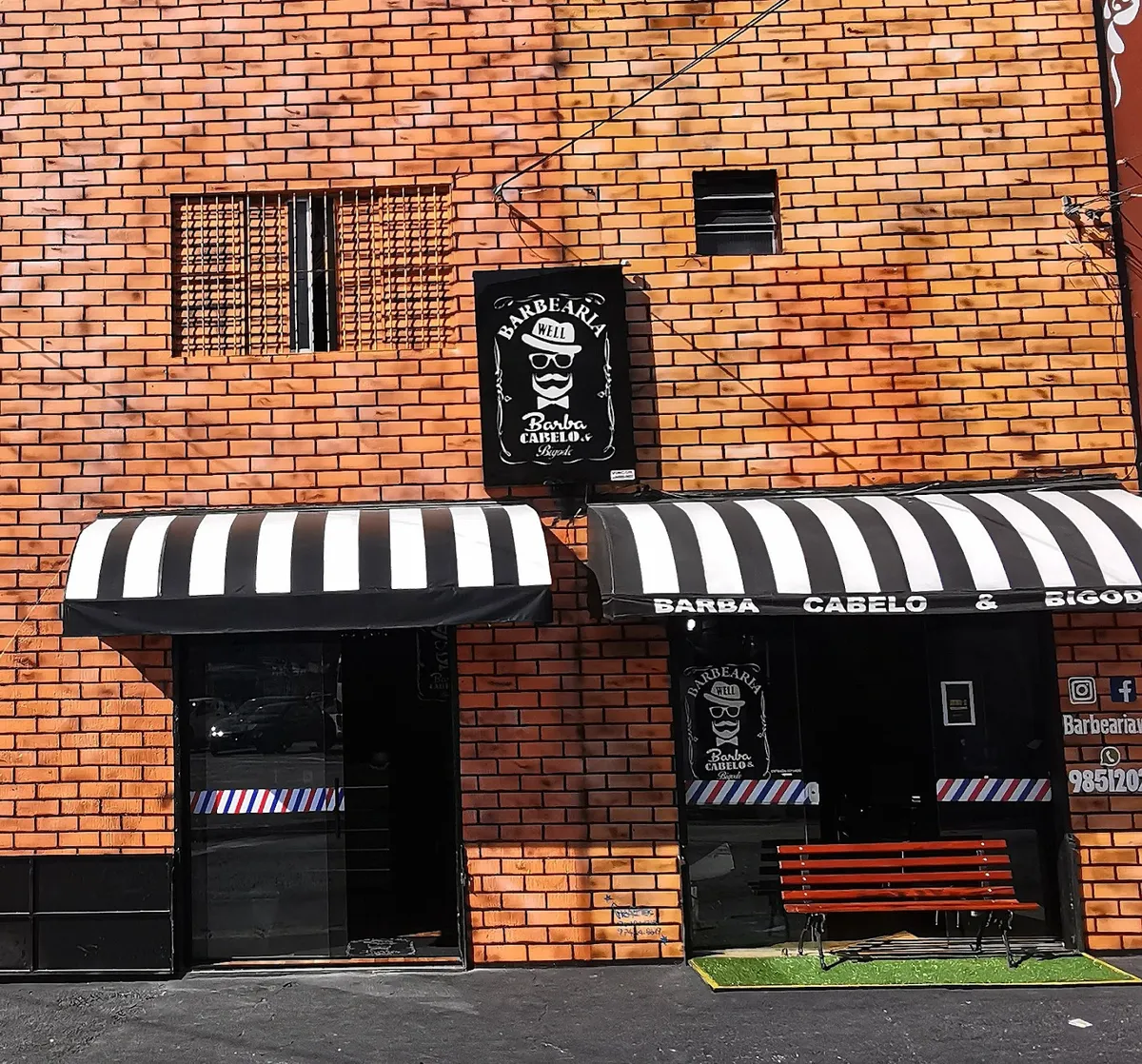 Fachada de tijolo da Barbearia Well com toldos listrados